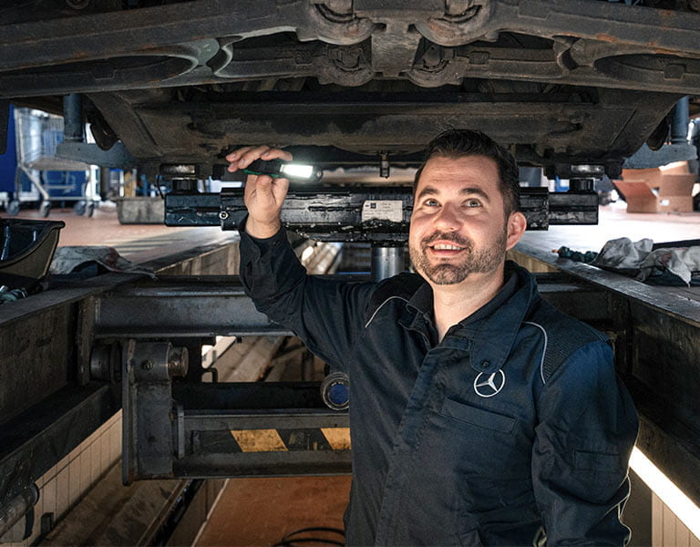 Pascal Stenger im Blaumann unter einem Lkw