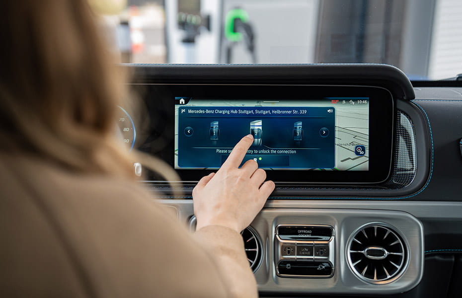 Frau stellt Ladestop im Infotainment System der vollelektrischen Mercedes-Benz G-Klasse ein
