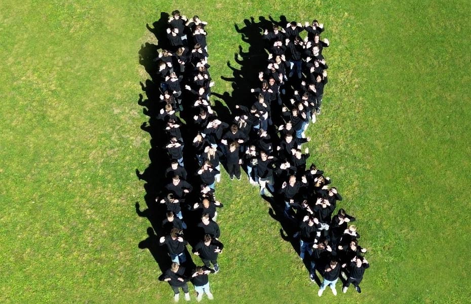 Kunzmann Mitarbeiter stehen in Forme eines "K" auf einer Wiese