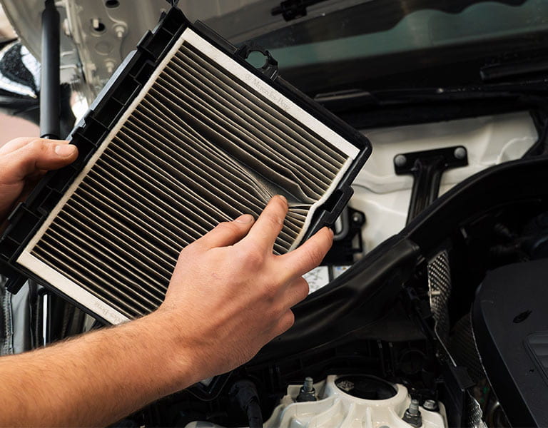 Klimaanlagenfilter ausgebaut und mit geöffneten Lamellen vor dem Motorraum