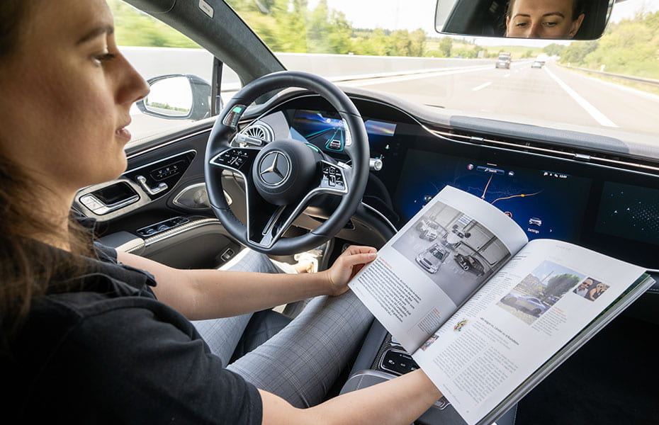 Frau liest eine Zeitschrift in einem fahrenden Mercedes-Benz EQS