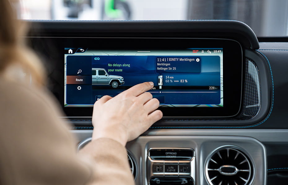 Frau bedient das Infotainmentsystem ihren vollelektrischen Mercedes-Benz