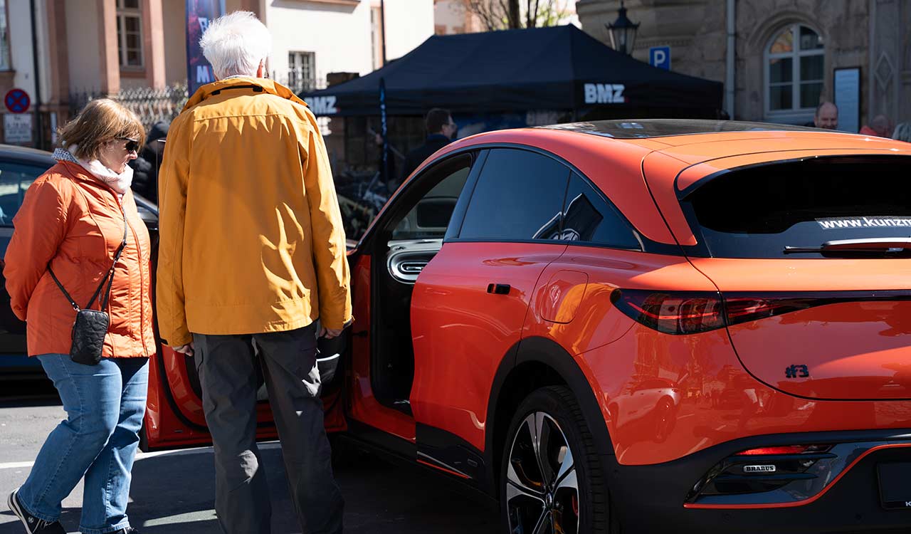 smart #3 in Organe mit geöffneter Tür wird durch Kunden auf der Mobilia 2025 in Aschaffenburg begutachtet