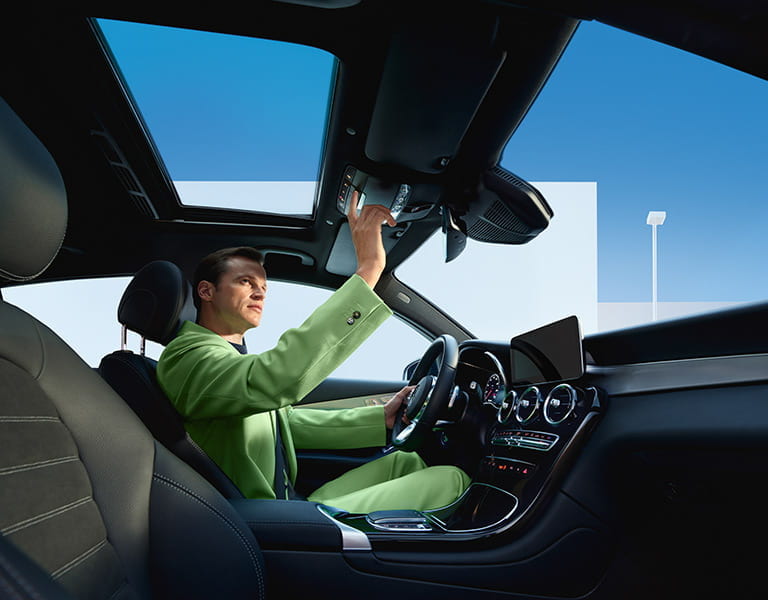 Mann in grünem Anzug beim Betätigen des Notrufknopfes im Mercedes-Benz