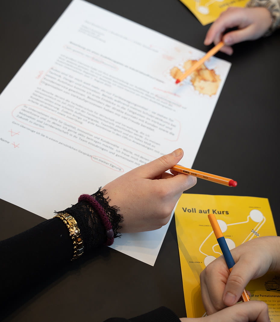Bewerbungsschreiben werden durch Schüler mit Stiften korrigiert