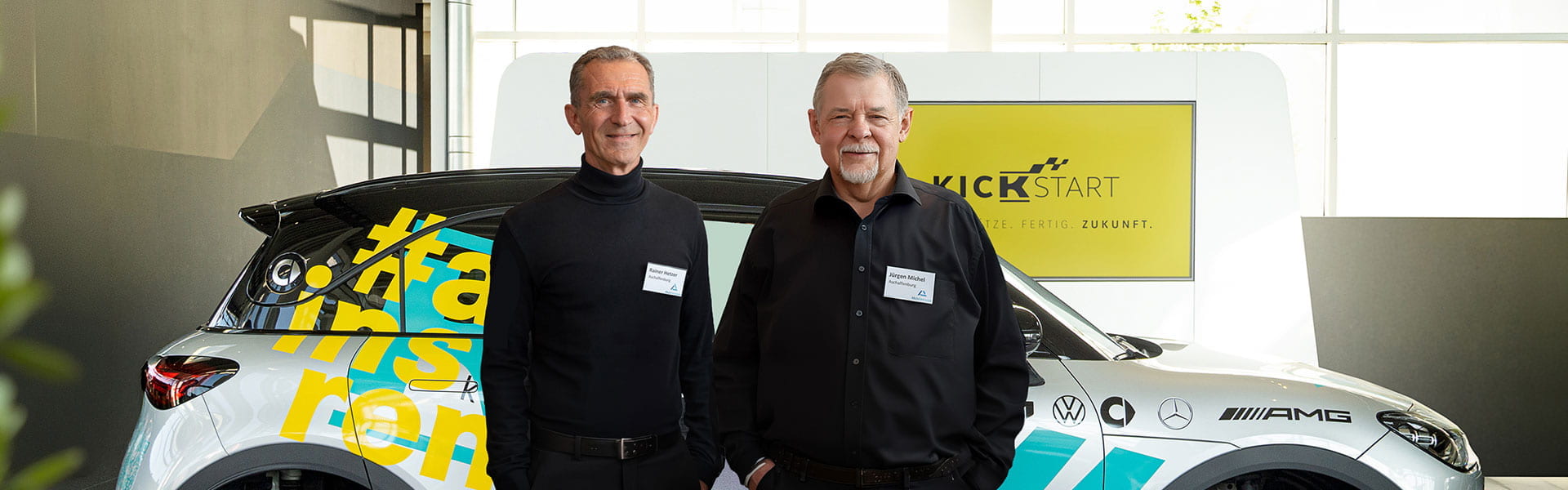 Dr. Jürgen Michel und Rainer Hetzer von den AktivSenioren Bayern im Kunzmann Showroom vor dem silbernen Ausbildungssmart