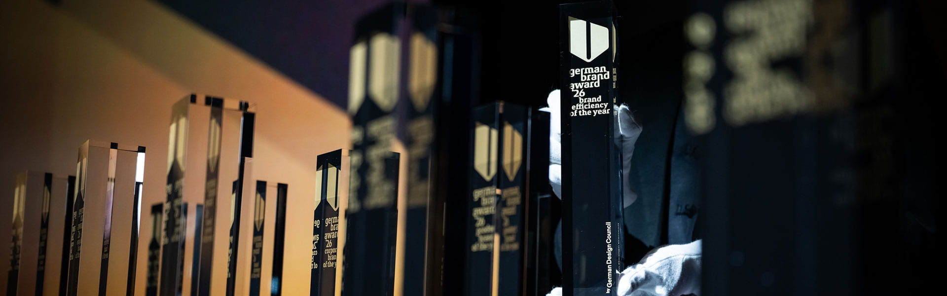 Pokale des German Brand Award platziert durch mit Samthandschuhen geschützten Händen