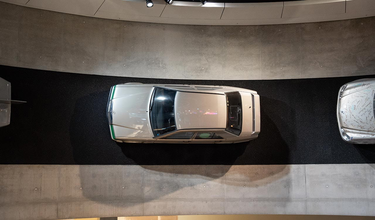 Silberner Mercedes-Benz 190E im Mercedes-Benz Museum an der Wand montiert