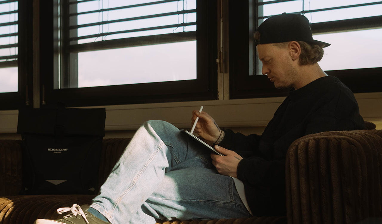 Tom Bilz beim Designen am iPad auf einer Couch in seinem Studio