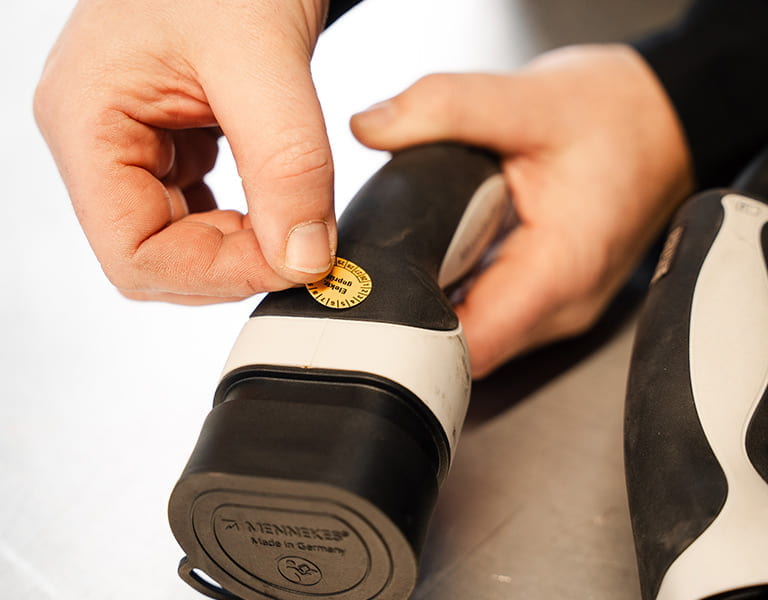 Prüfplakette wird auf ein Ladekabel geklebt