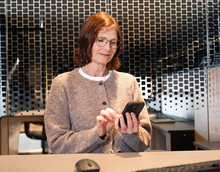 Vertrauensperson Birgit Reichert im Büro mit Smartphone in der Hand